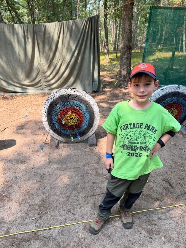 Scout standing beside an archery target