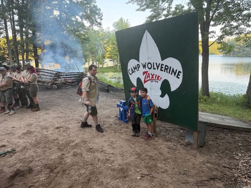Scout leader and Scouts posing at the Camp Wolverine gateway