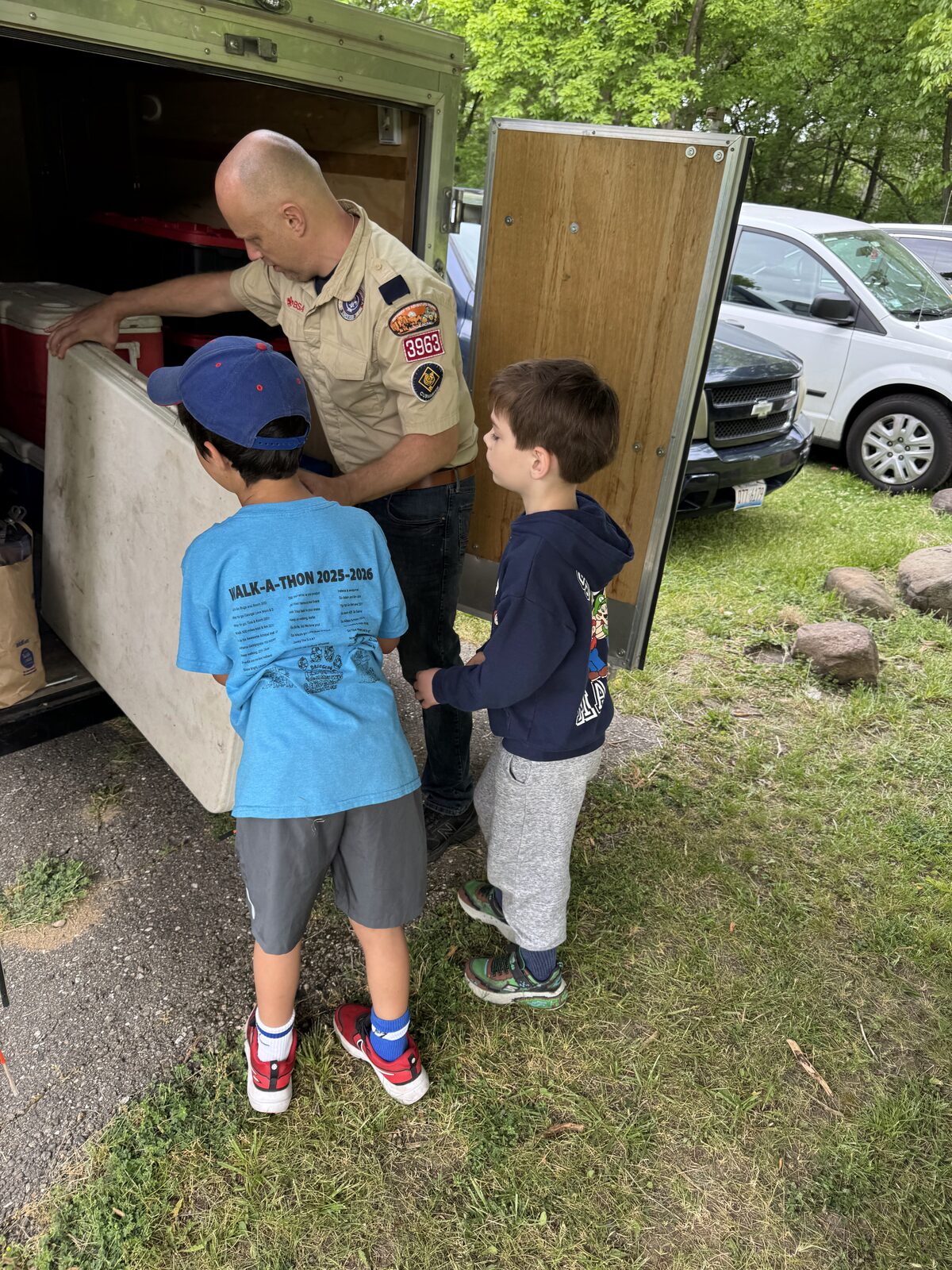 Scout leader teaching outdoor skills to two Scouts