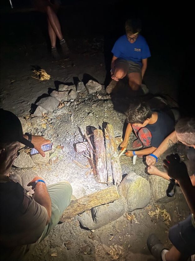 Scouts gathered around a campfire at night
