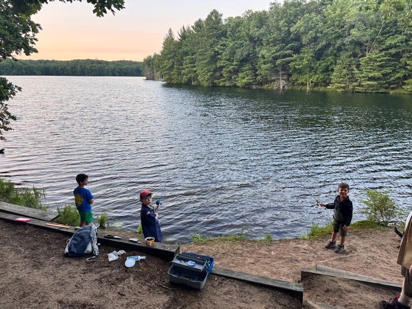Scouts fishing from a wooded lakeshore